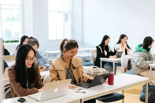 ELE female students smiling at desks